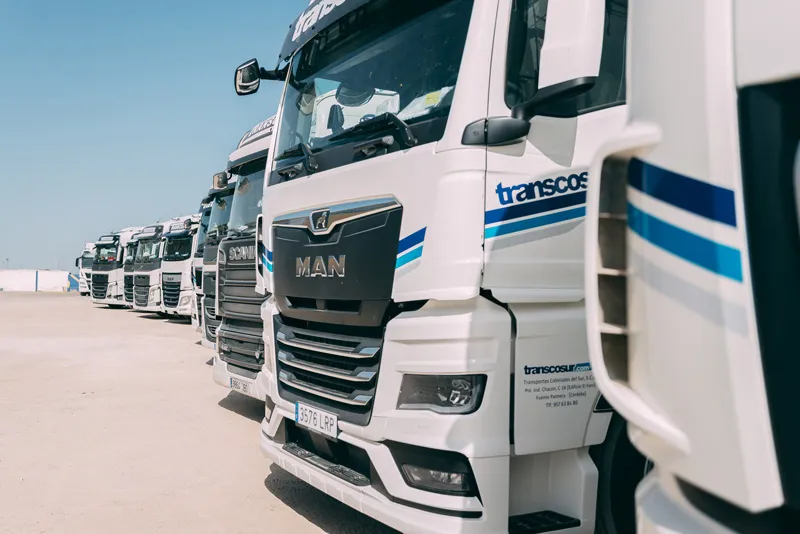 Gros plan d’un tracteur routier MAN blanc Transcosur avec d’autres camions derrière